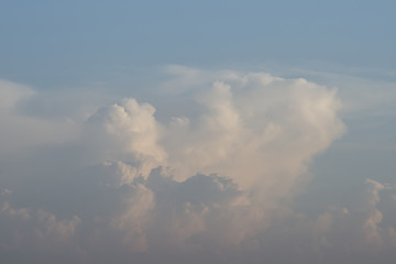 Beautiful fluffy white clouds in the light of the setting sun, background.