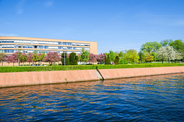 Magnus-Hirschfeld-Ufer with flowering trees, waterfront promenade and Federal Snake Complex in Berlin