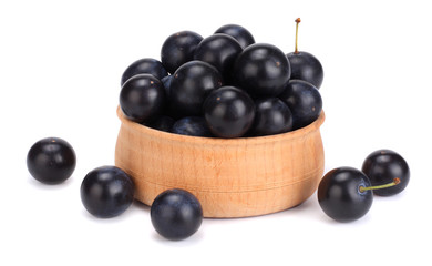 blackthorn berries in wooden bowl with green leaf isolated on white background