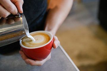 Fototapeta na wymiar Man pouring latte art at coffee shop cafe