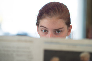 Skeptical or Bored Girl Reading Newspaper