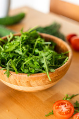 Salad with arugula cherry tomatoes and cucumbers in a wooden Bowl on a wooden table