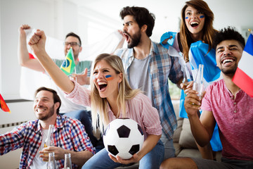 Soccer fans emotionally watching game in the living room.