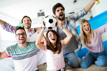 Cheerful group of friends watching football game on tv.