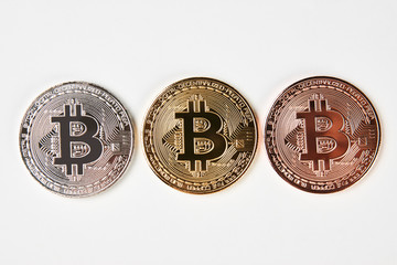 Bitcoins isolated on white background, close-up. Three bitcoin cryptocurrency coins made from gold silver and bronze metal