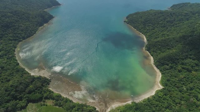 Aerial view of tropical beach in bay with turquoise water. Siwangag Cove. Coast of tropical island Palau with mountains covered rainforest. Santa Ana, province of Cagayan, Philippines.