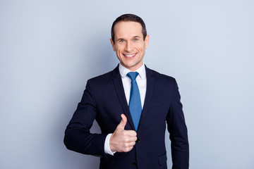 Attractive, executive, corporate, cheerful, positive politician, economist, financier in formal wear with tie, making thumb up, standing over gray background