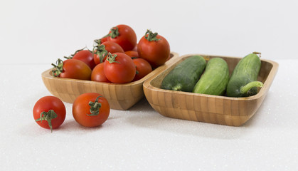 Fresh cucumbers and tomatoes in wooden bowl on the white background