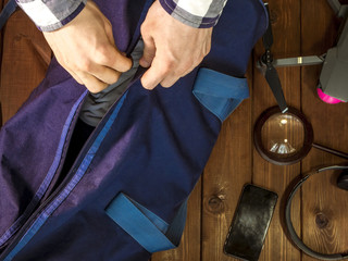 close up hand holding travel bag on the wooden table with accessories