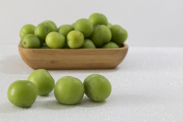 Green cherry-plum in wooden bowl