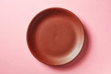 Brown plate on pink background, from above © bigacis