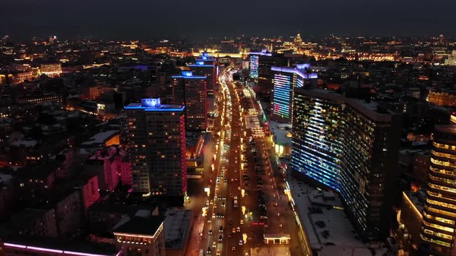 Bright lights of night Moscow from bird's eye view. Intensive traffic at New Arbat street in the heart of the city. Multistory houses illuminated with neon lights on the sides of the wide avenue.