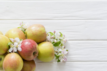 apple flowers and ripe apples on a white wooden background.