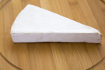 Brie cheese on wooden board. Closeup
