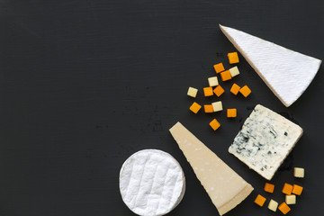Various types of cheese on dark background. Food for romantic. Copy space. Flat lay. From above, top view.