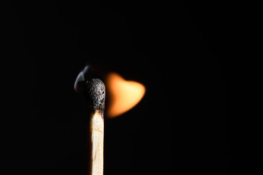 Match with the fading flame beveled on its side on a black background closeup