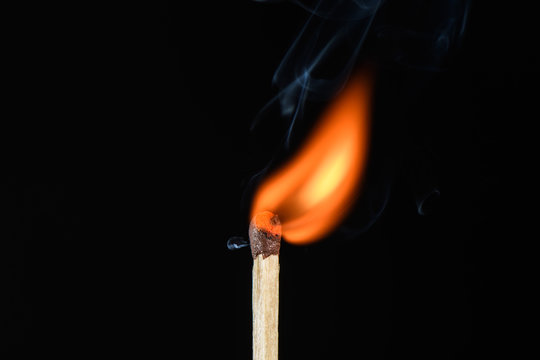Match with a flame flaring point beveled on its side on a black background closeup