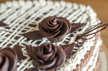 Homemade dark sponge cake with butter cream and chocolate roses