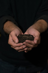 Man in black shirt holding pile of dirt