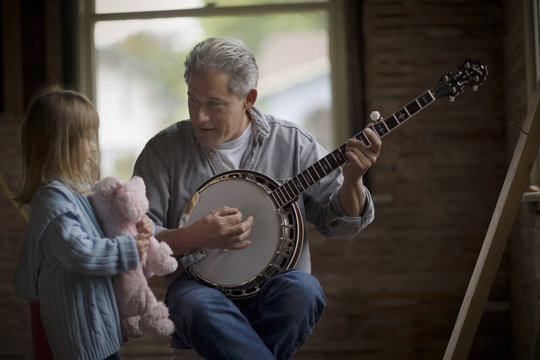 Father playing banjo for his daughter at home