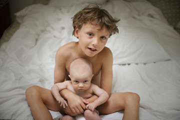 View of a small boy sitting with a baby.