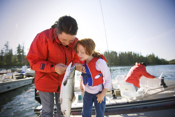 Teenage girl and her younger sister looking inside the mouth of a caught fish.
