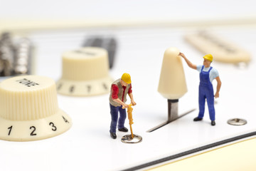 Miniature Workers Fixing The Control Switch Of An Electric Guitar