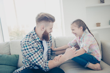 Obraz premium Family with one parent, stylish father with good humor kidding with excited laughing comic daughter on sofa in livingroom best friends dreamday funny game babysitting