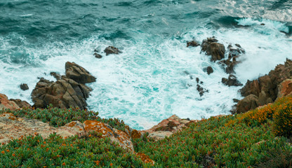 Waves knock on the stone cliff of the sardinian coast