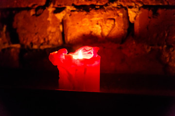 Candle burns on the background of an old brick wall