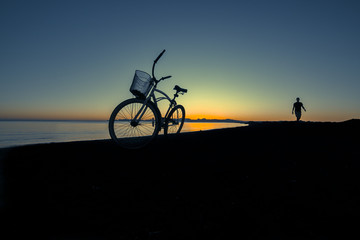Obraz premium silueta de bicicleta y hombre caminando en la bahía