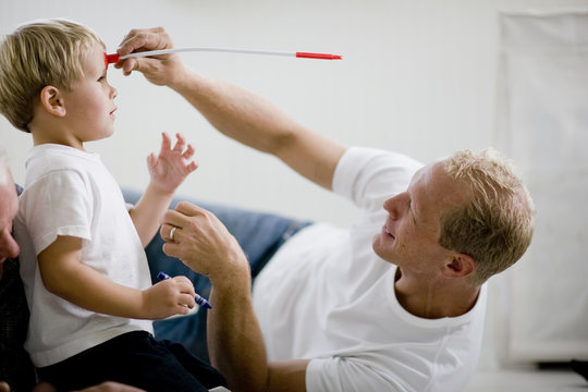 Man sticking toy arrow to son's head