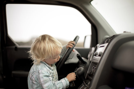 Curious boy trying to insert keys into the ignition of car