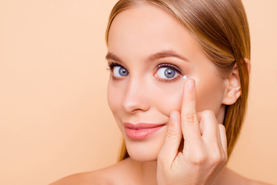 Portrait Of Pretty, Charming, Nude, Natural Cute, Cheerful Girl Putting Crystalline Lens In Left Eye With Hand, Forefinger Looking At Camera Isolated On Beige Background