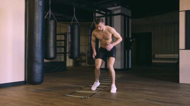 Young athletic man training with coordination ladder