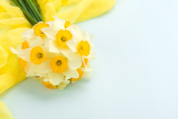 Daffodil bouquet with yellow textile decoration on blue pastel background with copy space.
