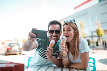 Young man is taking selfie with his girlfriend while having ice-cream in cone