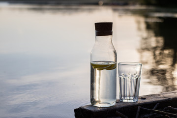 Obraz premium A bottle of water with lemon and a glass. Bridge on which stands a refreshing drink.