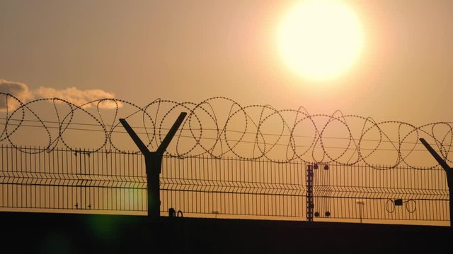Barbed wire fence with Twilight sky to feel Silent and lonely and want freedom. Barbed wire steel wall against the immigration in Europe.