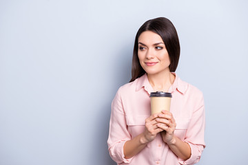 Portrait with empty place of dreamy thoughtful cute trendy woman having mug with warm tea in hands looking at copy space isolated on grey background
