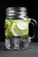 Rejuvenating drink, cocktail, tea, water with lemon, inbet, mint, cucumber in clear glass on a black background. Improvement and purification of the body. Detox.