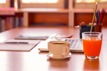 Office table with notepad, computer, pen and coffee cup