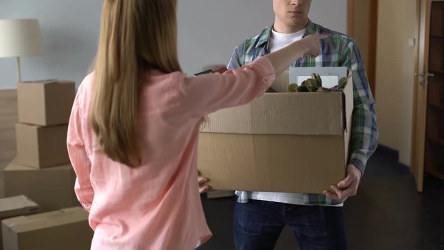 Angry and offended woman expelling man with all stuff out of house, break-up
