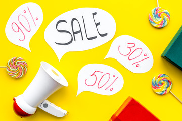 Sale concept with megaphone. Declare the sale. Electronic megaphone near word sale in cloud, gift boxes and sweets on yellow background top view