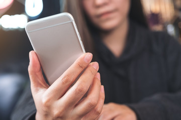Closeup image of a woman holding , using and looking at smart phone