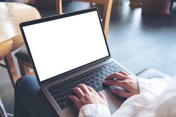 Mockup image of woman's hands using and typing on laptop with blank white desktop screen while sitting in cafe