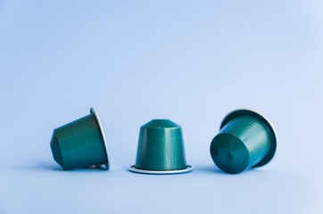 Beautiful colored coffee capsules on light blue background.