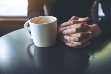 Closeup image of a woman holding hand and drinking hot coffee in cafe