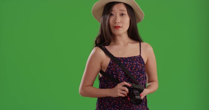 Happy young tourist woman taking pictures with camera in front of greenscreen
