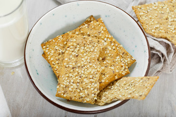 Healthy food. Fitness cookies with chia seeds, flax and pumpkin in bowl on white wooden background with glass milk close up